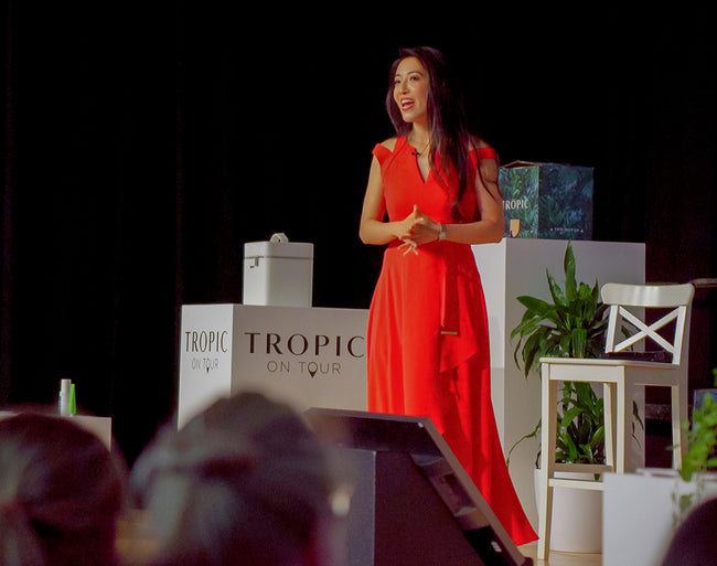 Susie Ma on stage at a Tropic on Tour event wearing a red dress